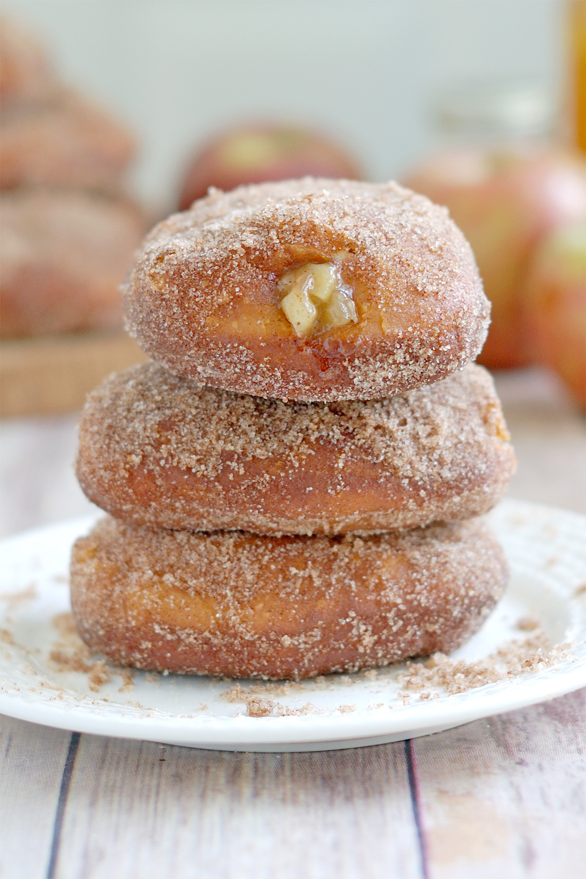 three apple filled donuts on a plate.