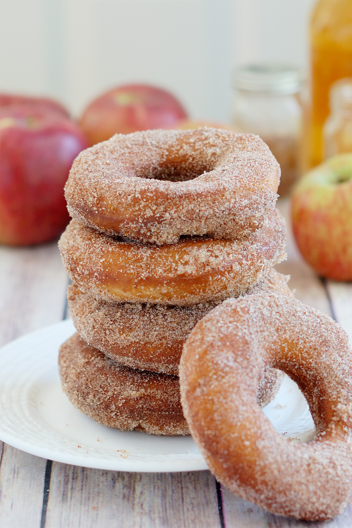 a stack of apple cider donuts on a white plate. 