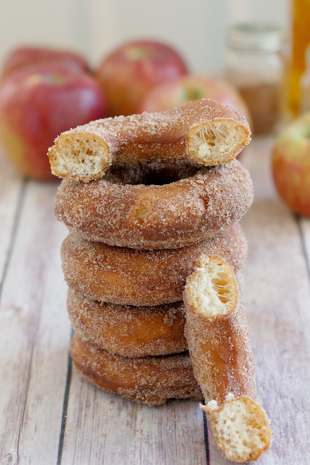 a stack of apple cider donuts with the top one split open. 