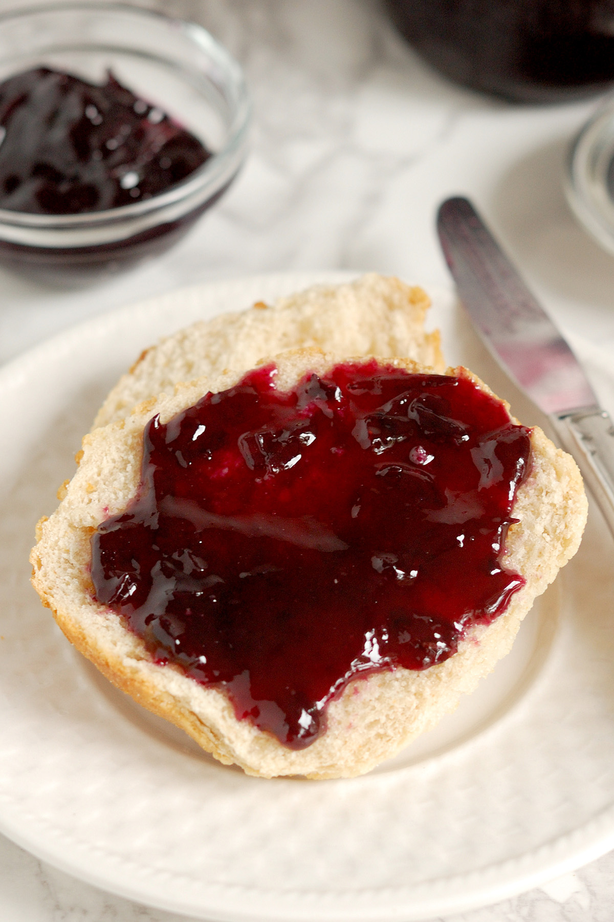 a piece of bread on a white plate with homemade concord grape jam.