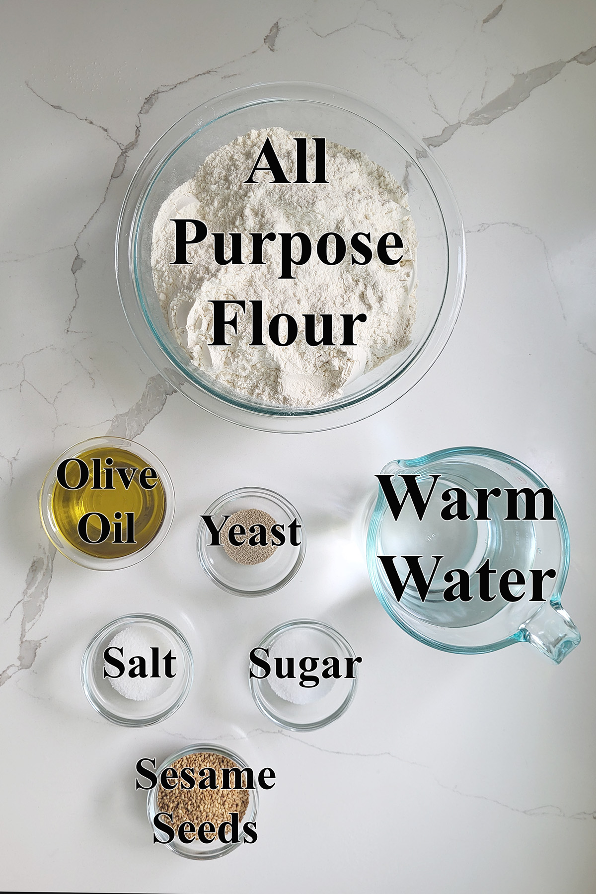 ingredients for italian bread in glass bowls on a white surface.