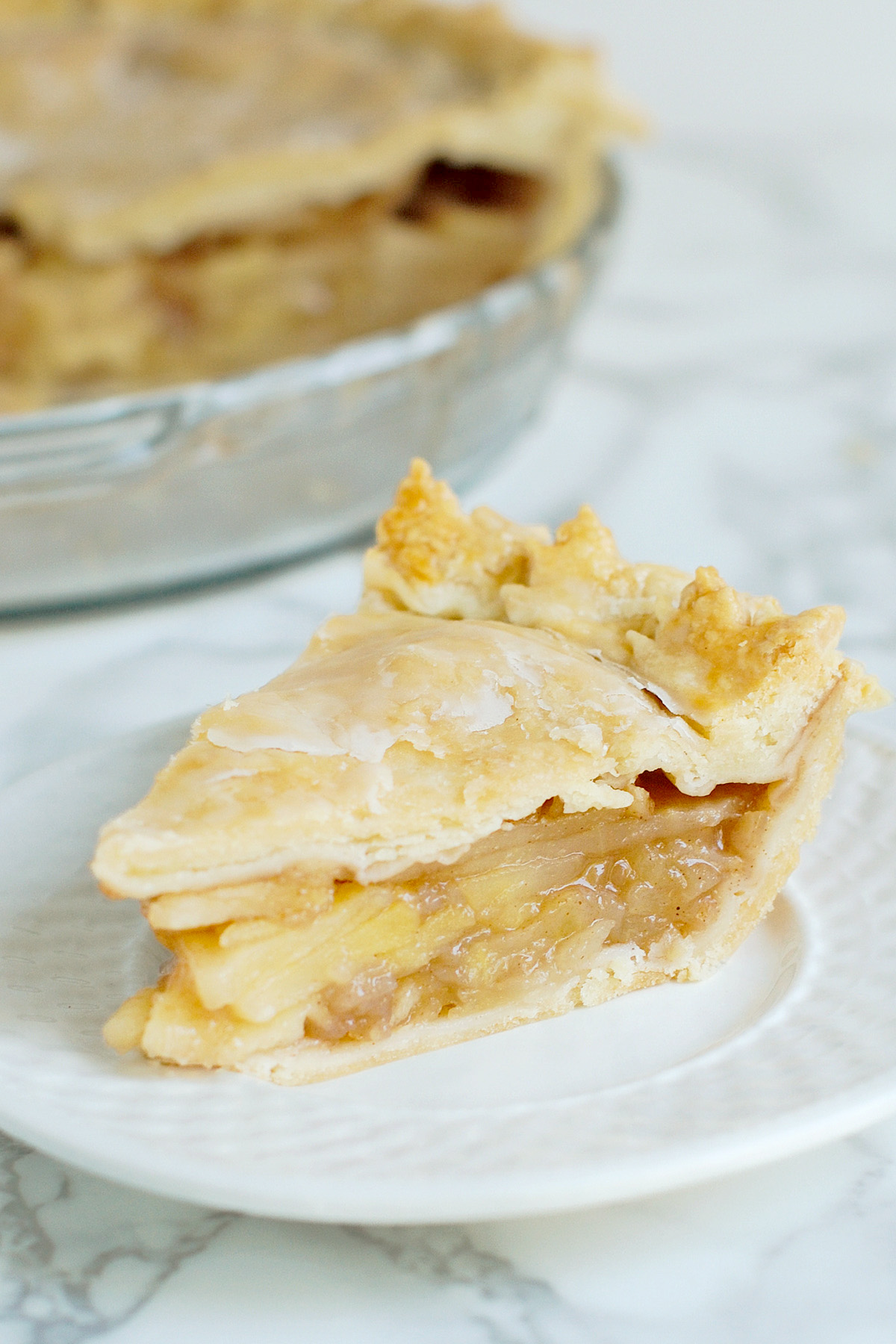 a slice of maple apple pie on a white plate.