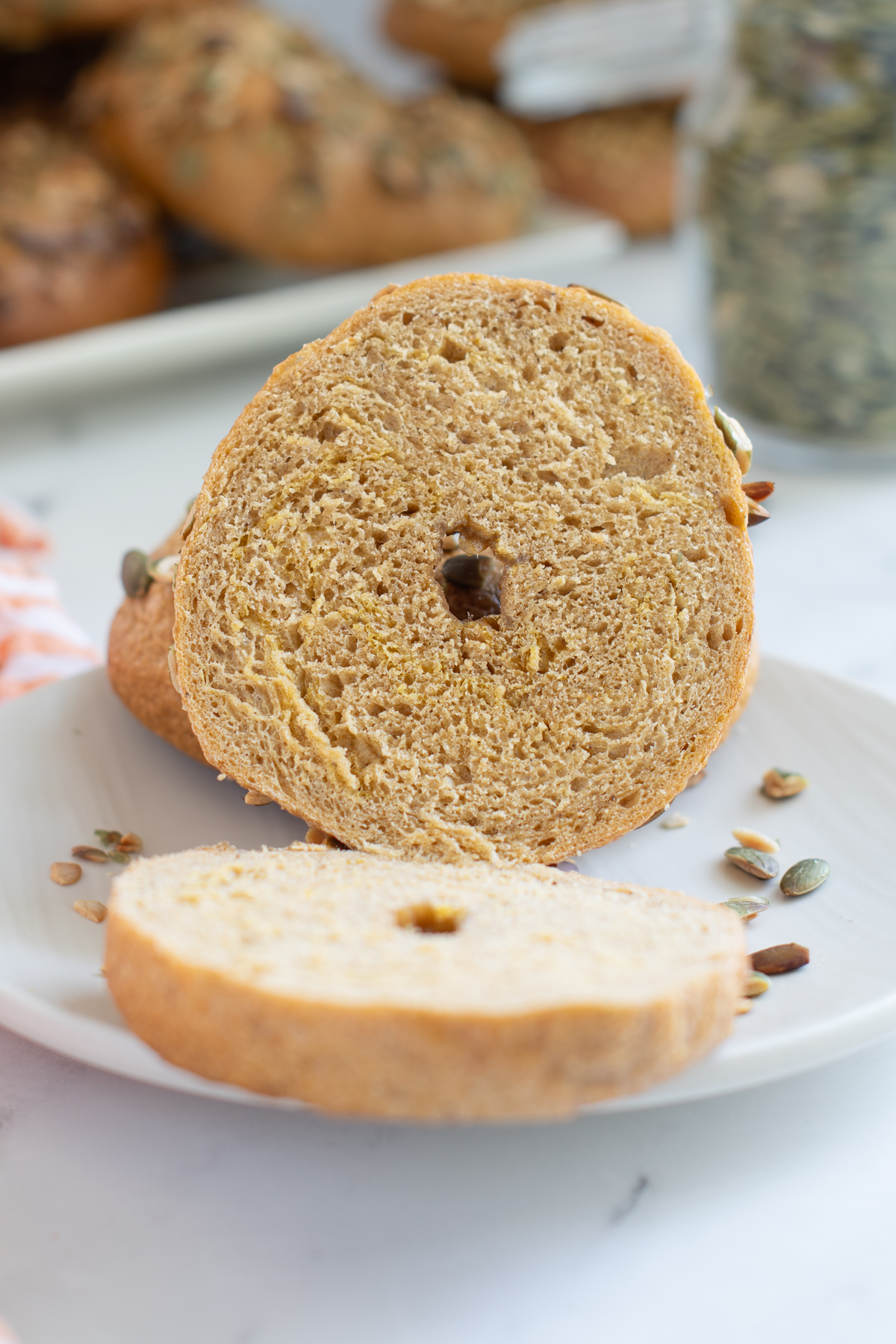 a cut-open pumpkin bagel on a white plate.