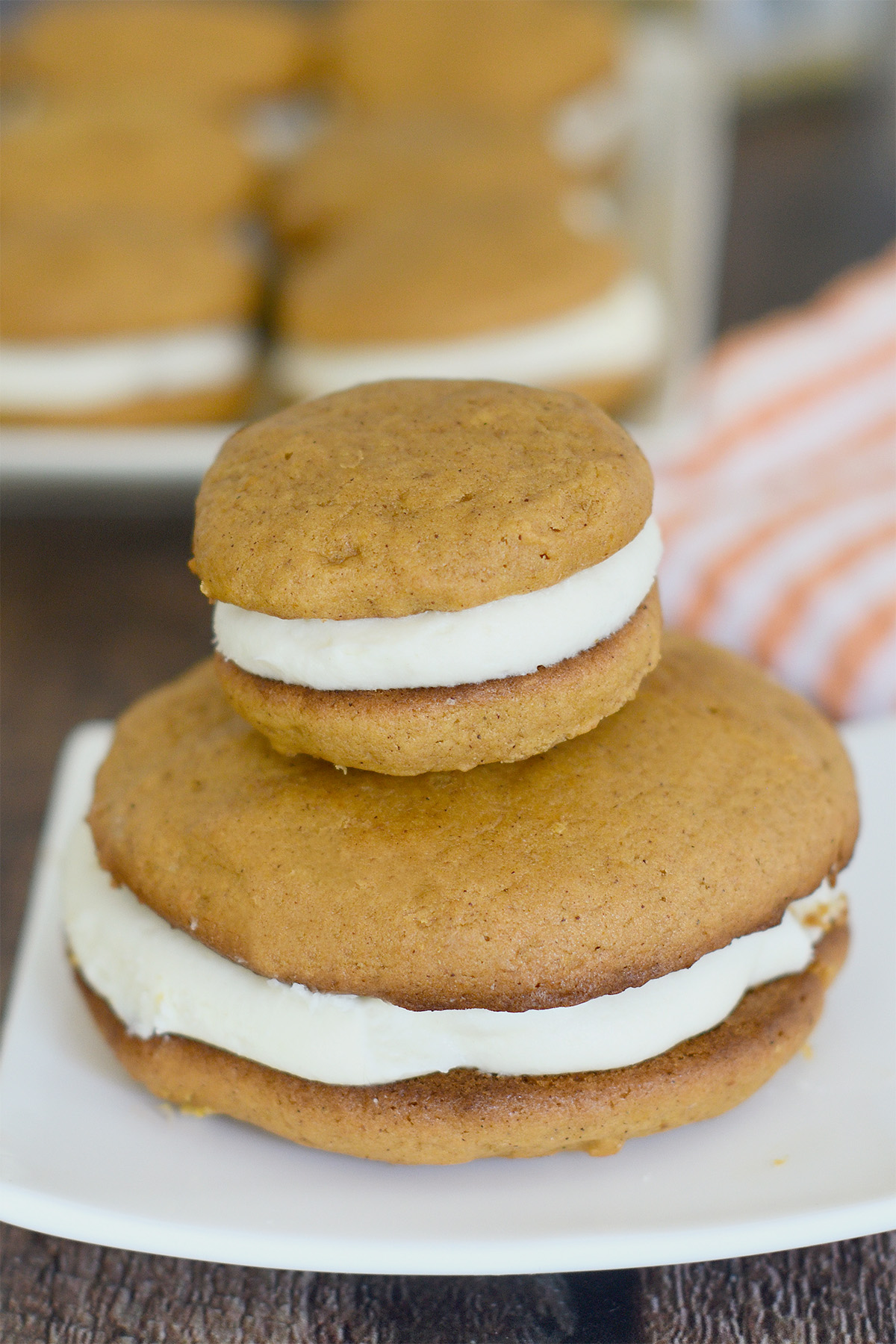a large and a small pumpkin whoopie pie on a white plate.