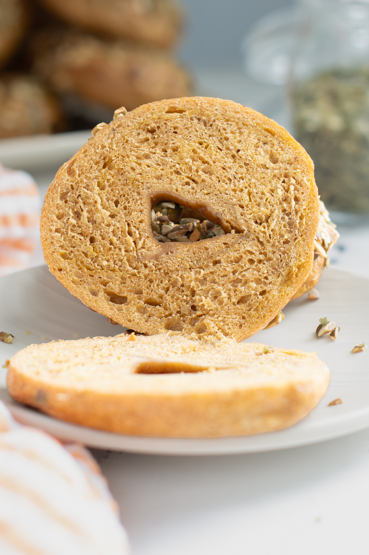 a split sourdough pumpkin bagel on a white plate.
