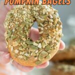 a hand holding a seeded sourdough pumpkin bagel.
