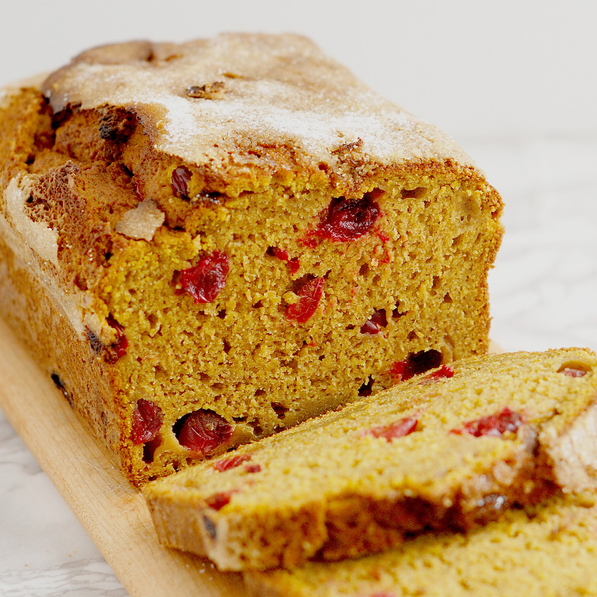 a sliced loaf of sourdough discard pumpkin bread on a wood cutting board.