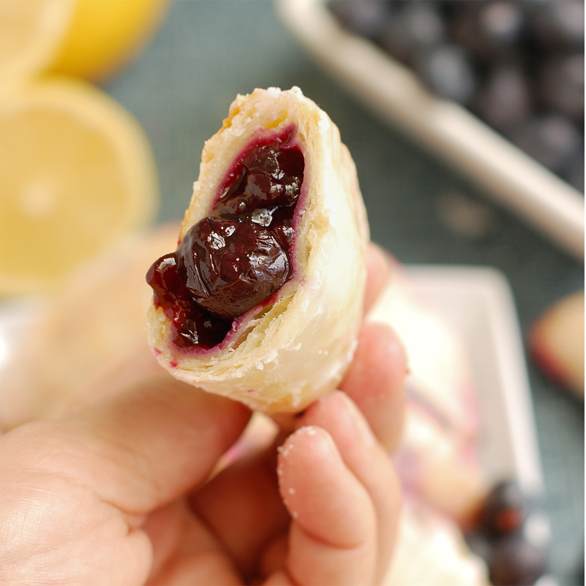a hand holding half of a blueberry hand pie.