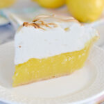 a slice of lemon meringue pie on a white plate.