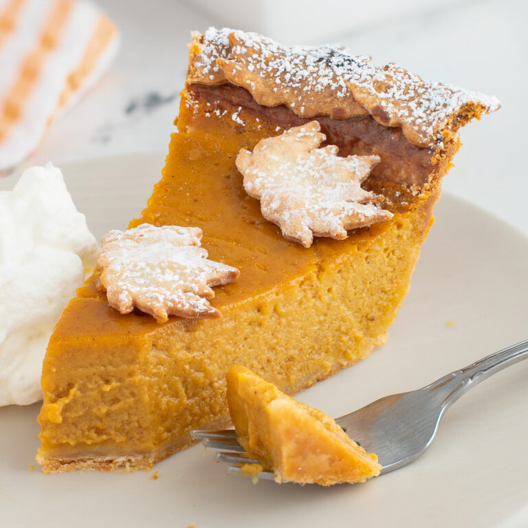 a slice of pumpkin pie with a fork on a white plate.