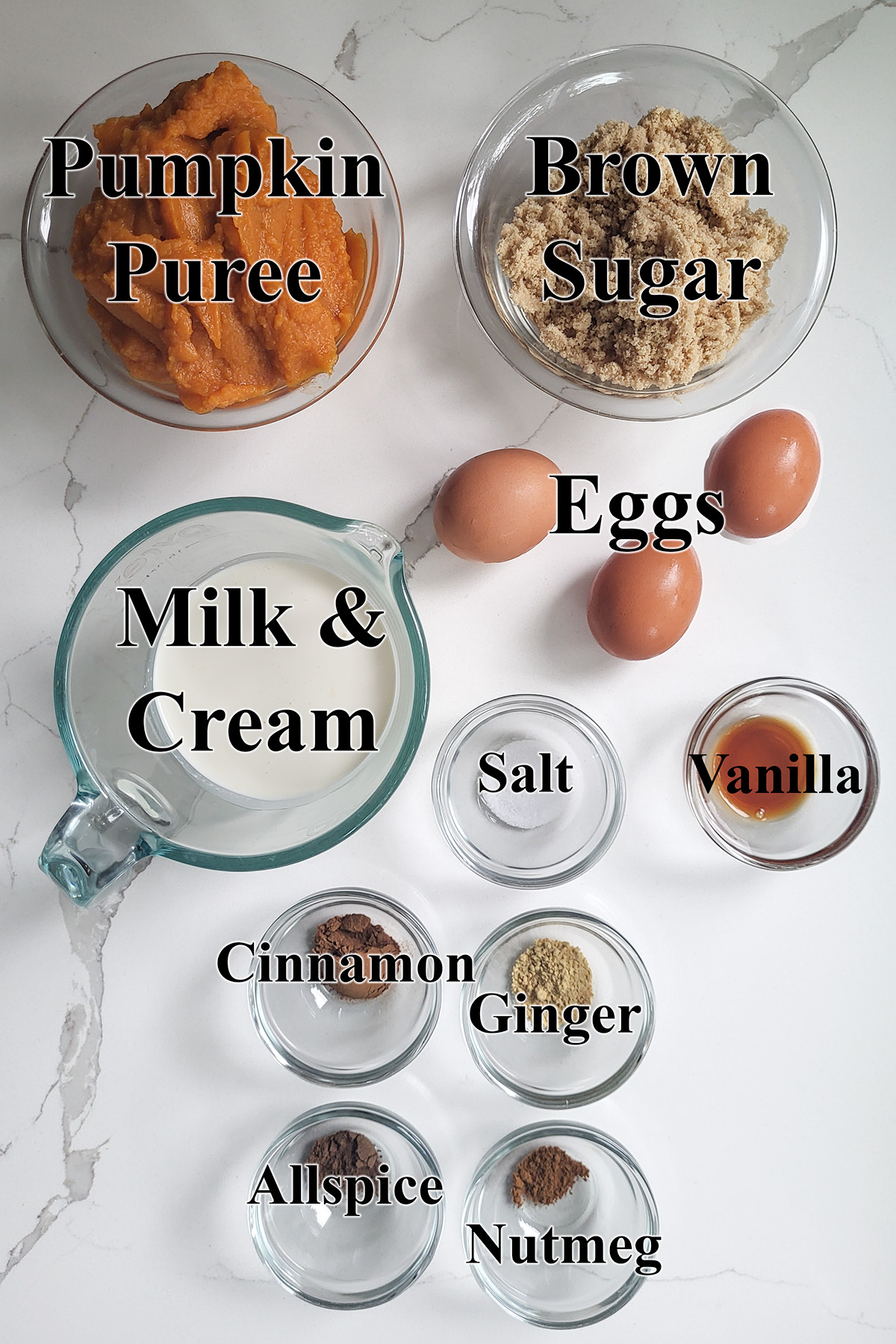 ingredients for classic pumpkin pie in glass bowls on a white surface.